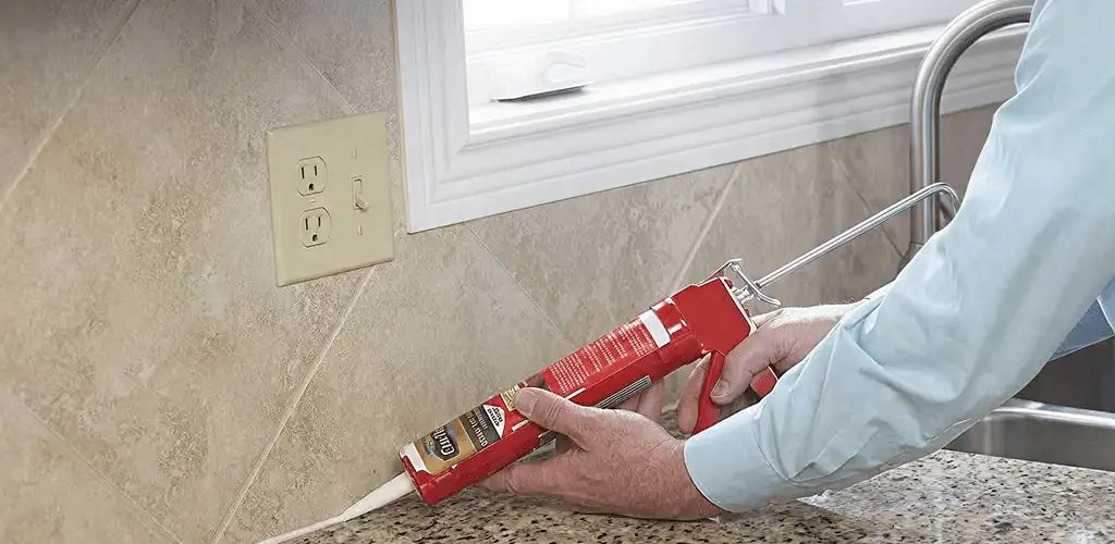 Handyman applying caulk along a kitchen backsplash and countertop seam in Tacoma, WA