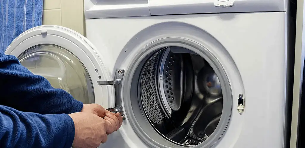 Washing machine repair handyman checking a front-load washer door and latch in Tacoma, WA