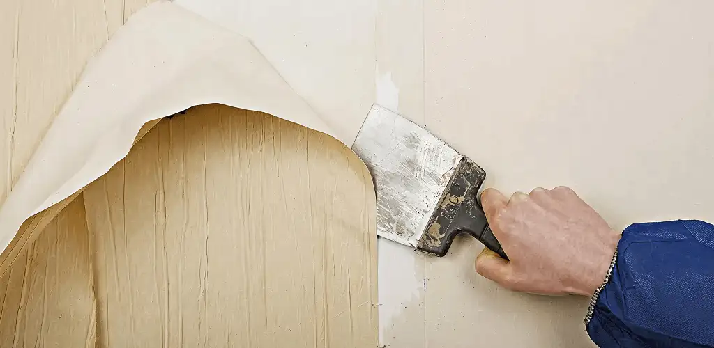 Handyman removing wallpaper with a scraper for wall preparation in Tacoma, WA