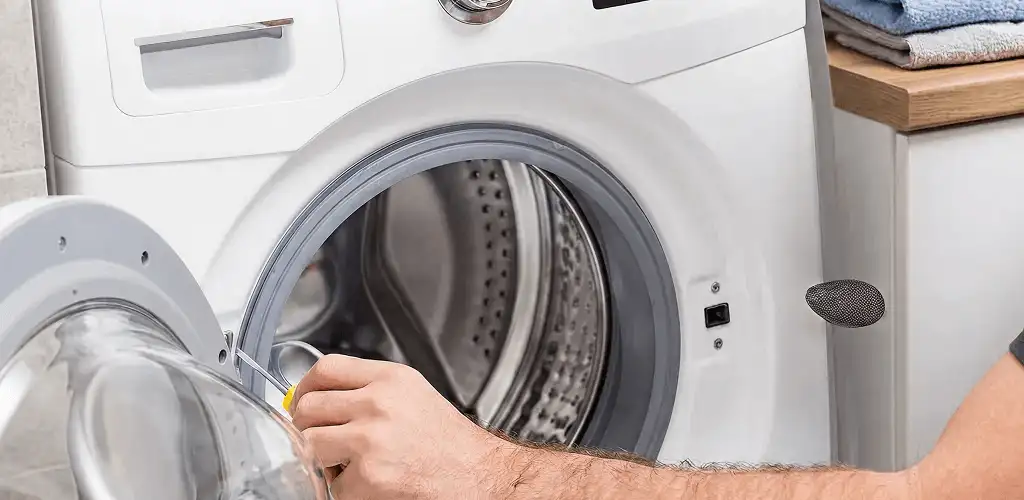Handyman repairing a front-load washing machine and inspecting the drum in Tacoma, WA