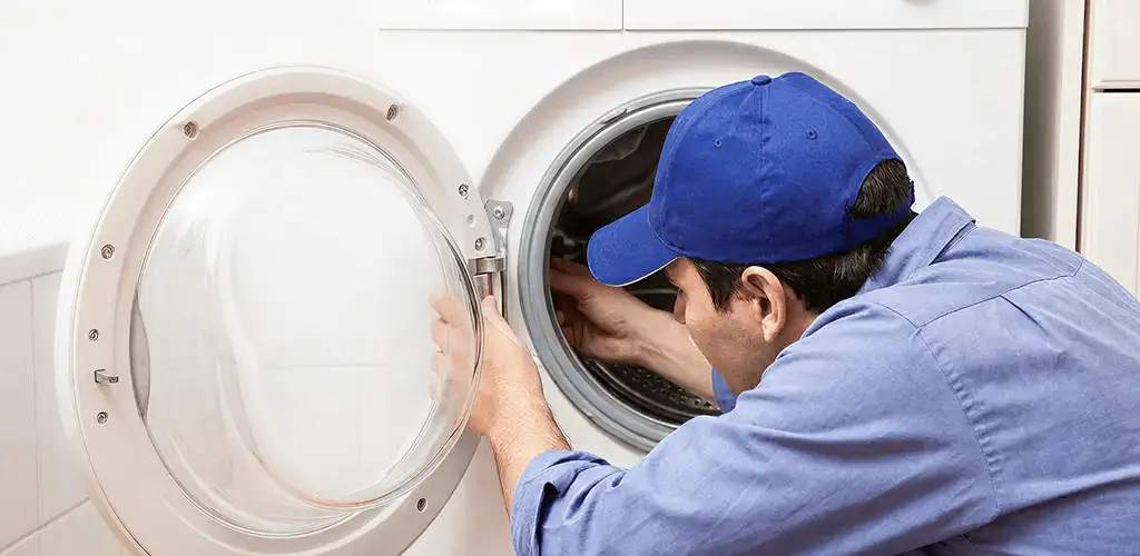 Washing machine repair handyman inspecting a front-load washer drum in Tacoma, WA