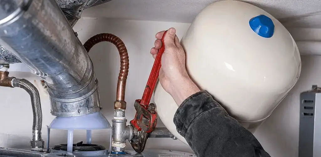Water heater repair technician tightening plumbing connections near a tank unit in Tacoma, WA