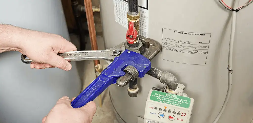 Water heater repair technician tightening the shutoff valve and supply line in Tacoma, WA